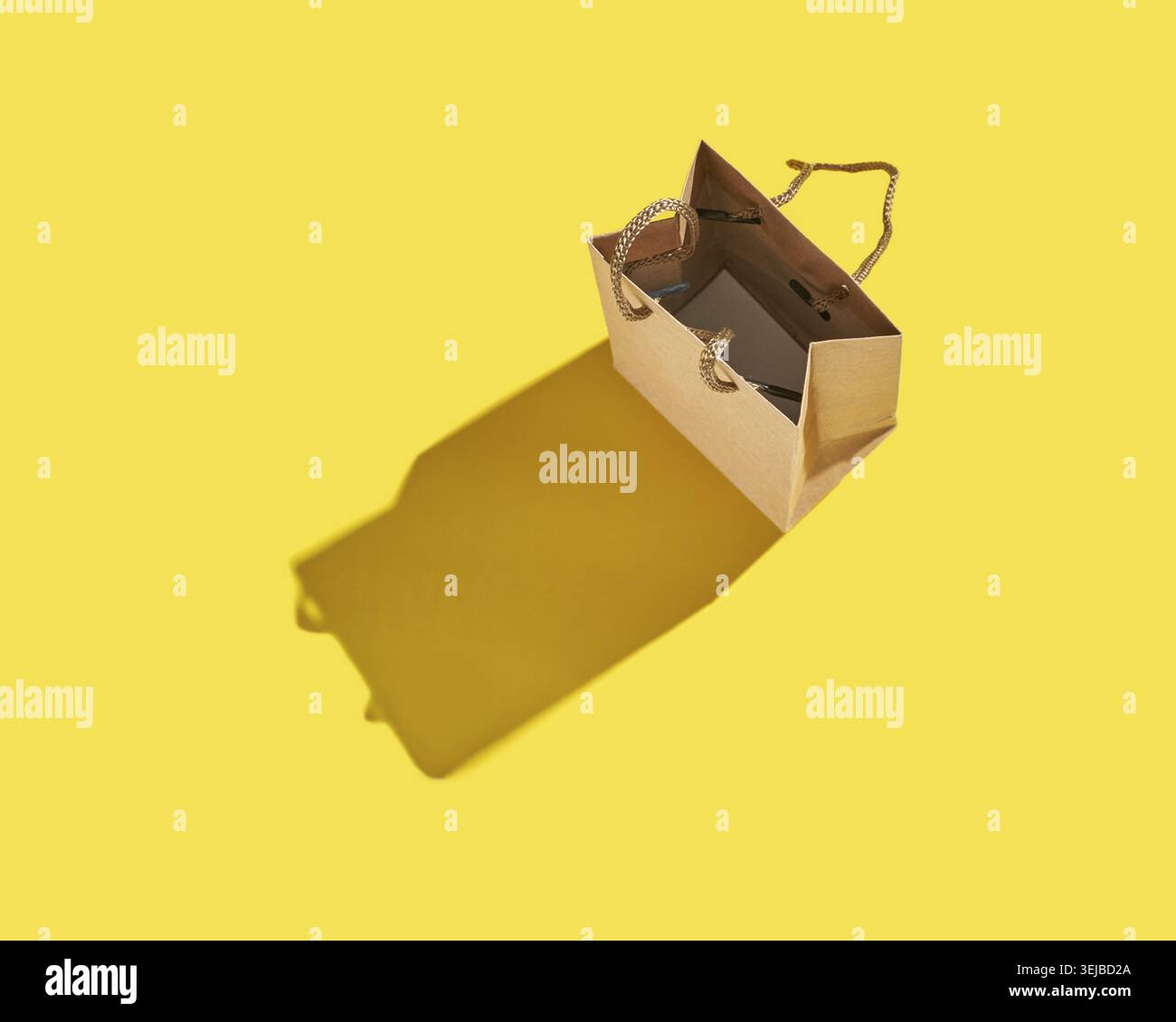 Open brown paper bag with shadow on bright yellow background minimalist composition Stock Photo