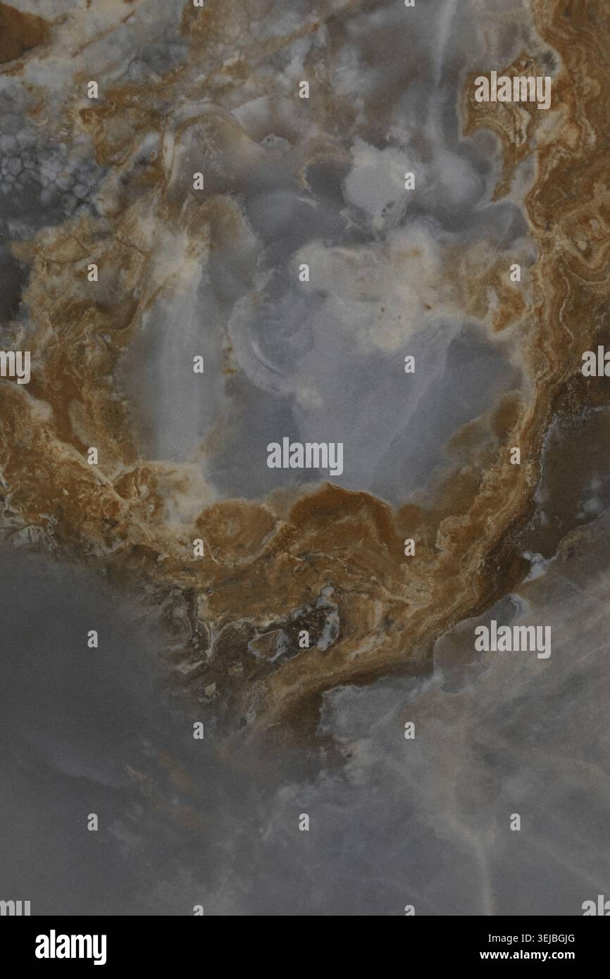 Swirling patterns of grey, brown, and white create a beautiful natural stone surface. The design mimics the movement of water and highlights unique fo Stock Photo