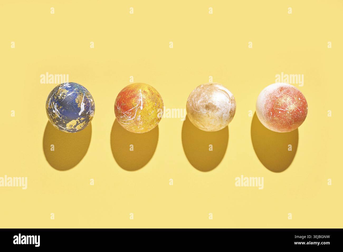 Colorful marbled balls on yellow background with shadows casting patterns Stock Photo