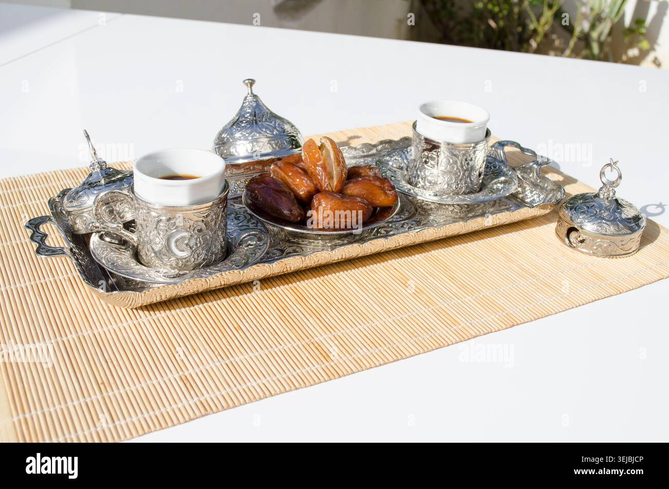 Arabic coffee cups served with fresh dates in sunlight. Stock Photo