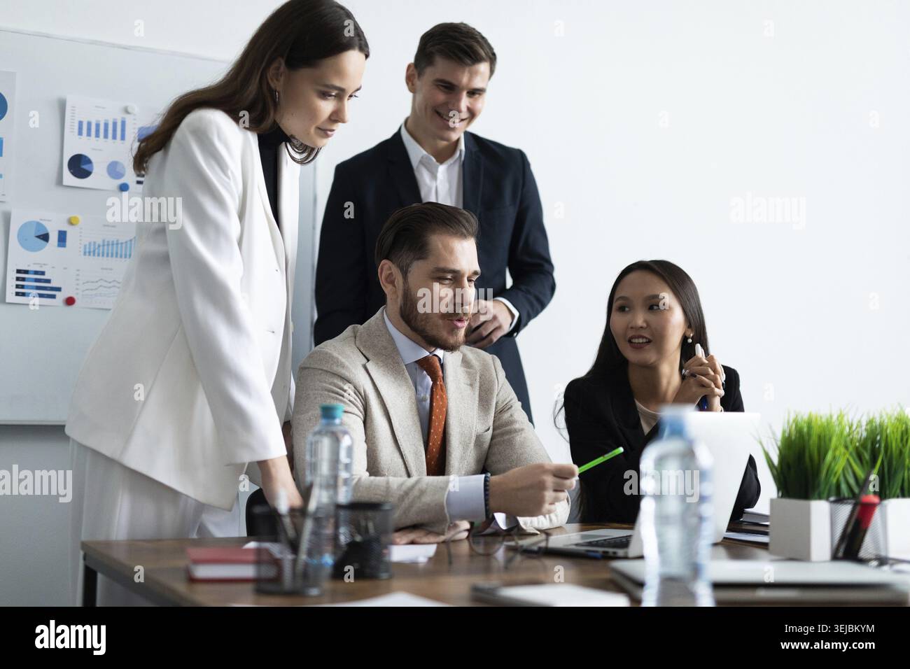 Smiling diverse colleagues gather in boardroom brainstorm discuss financial statistics together Stock Photo