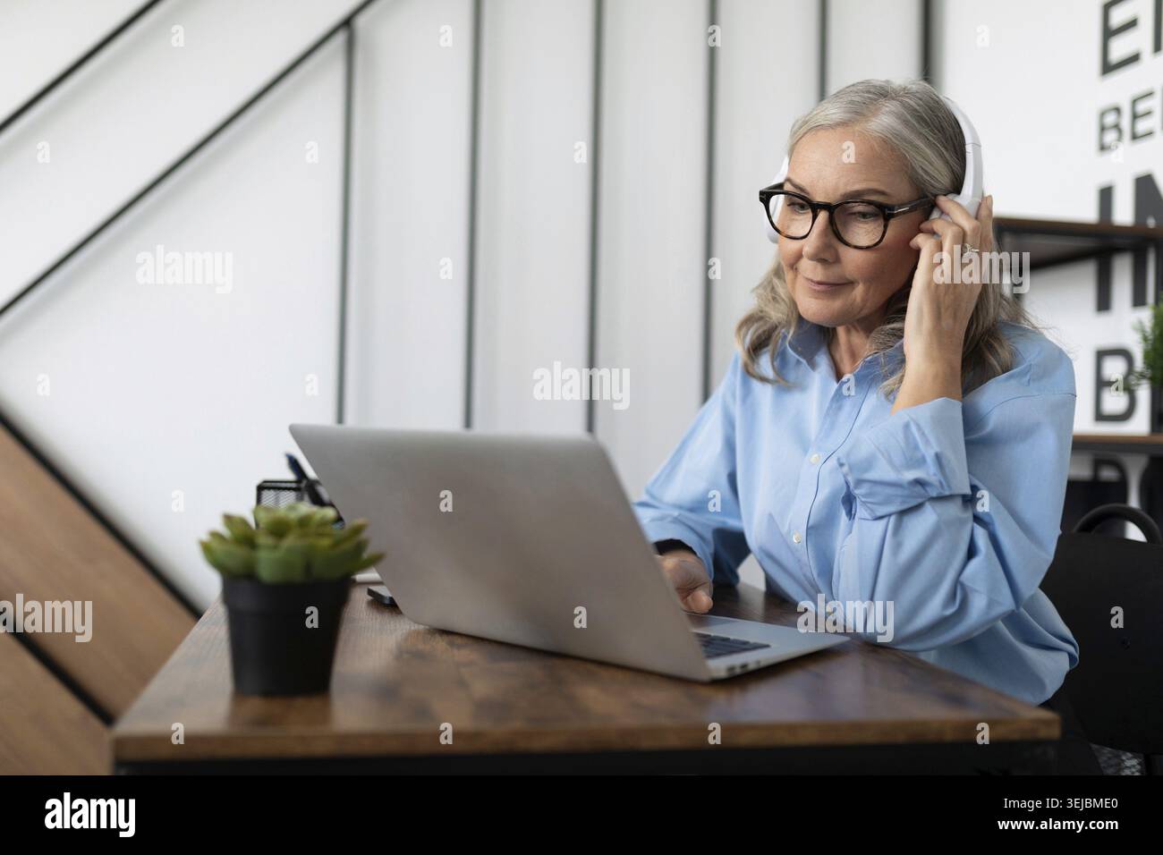 Caucasian businesswoman in headphones watching webinar on laptop in office Stock Photo