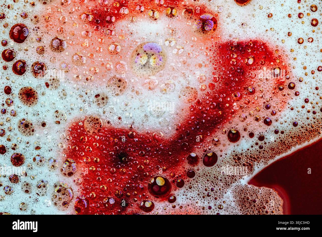 Detergent foam with bubbles and colored bubbles in red liquid Stock Photo