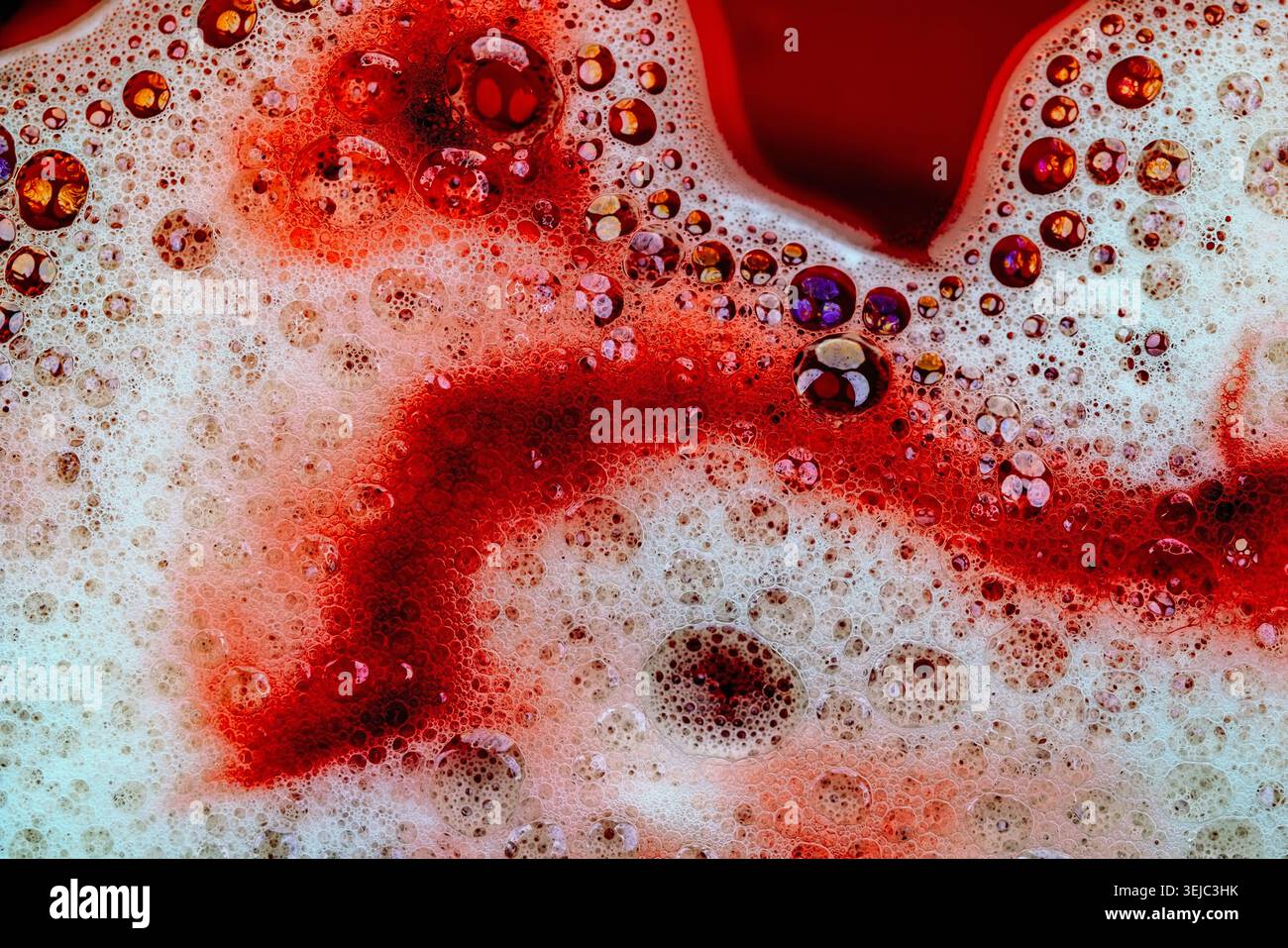 Detergent foam with bubbles and colored bubbles in red liquid Stock Photo