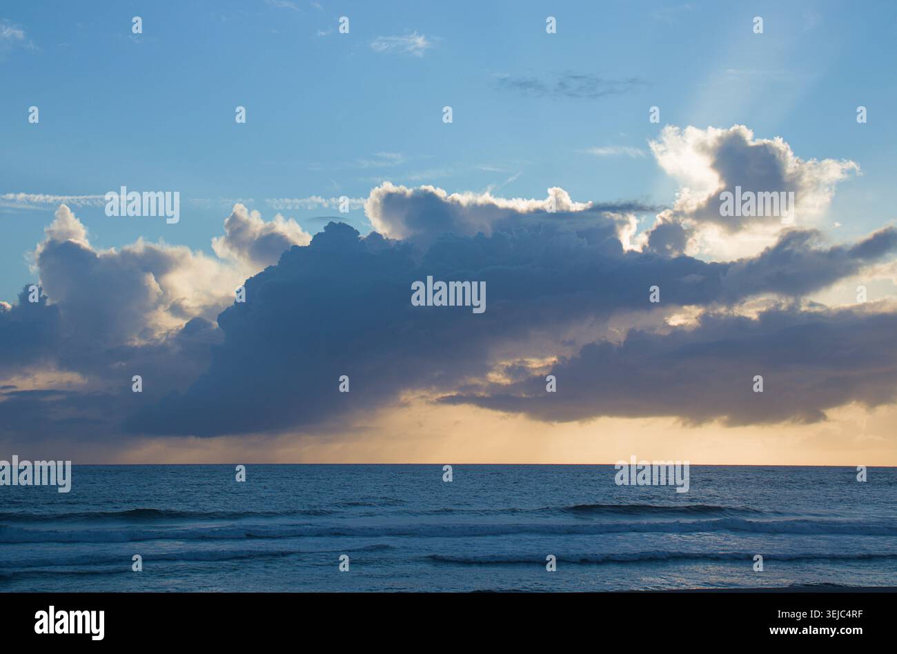 Majestic Sunset Over the Ocean with Dramatic Cloud Formations Stock Photo