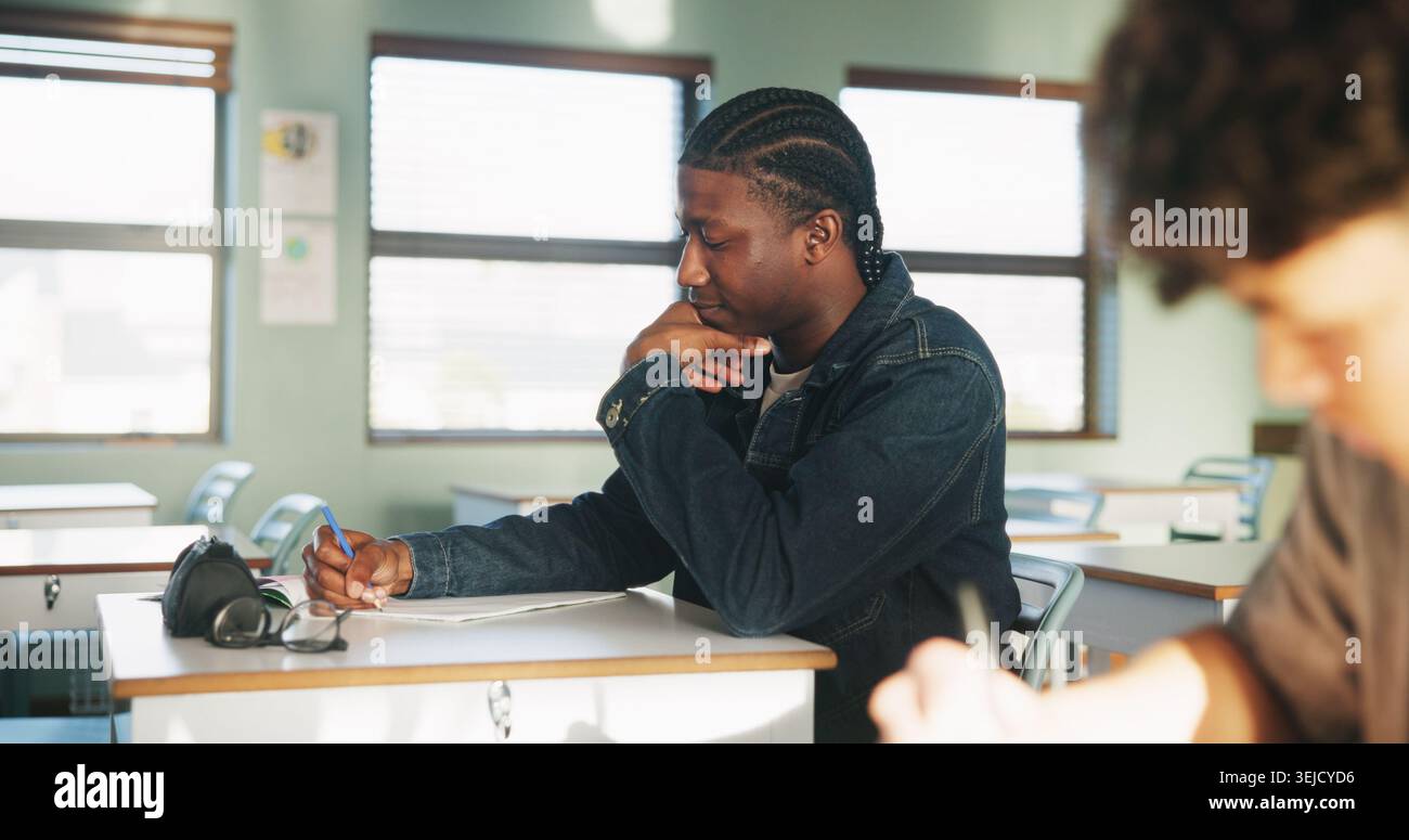 Student, thinking or writing in classroom with college assignment, education or english essay idea. Man, notes or learning in university with problem Stock Photo