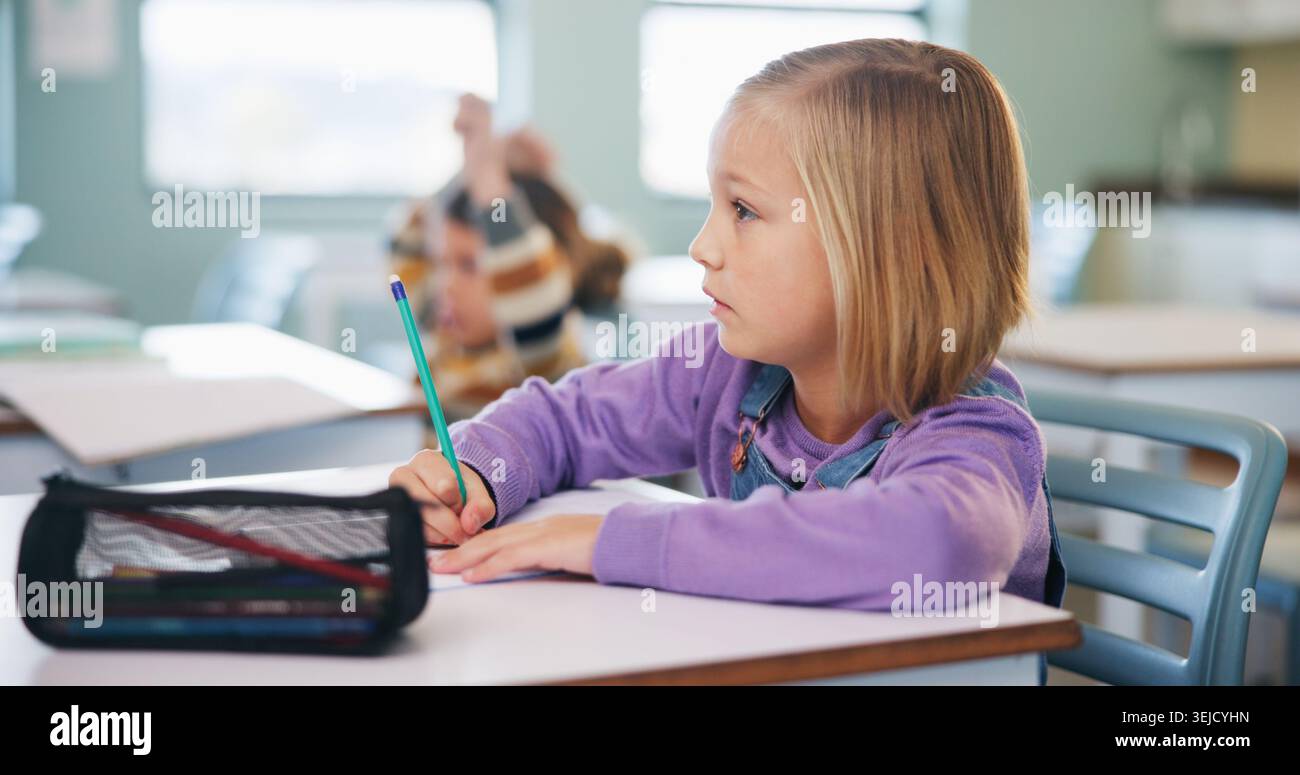 Writing, learning and exam with girl in classroom for test, child development and knowledge. Education, notebook and lesson with student on school Stock Photo