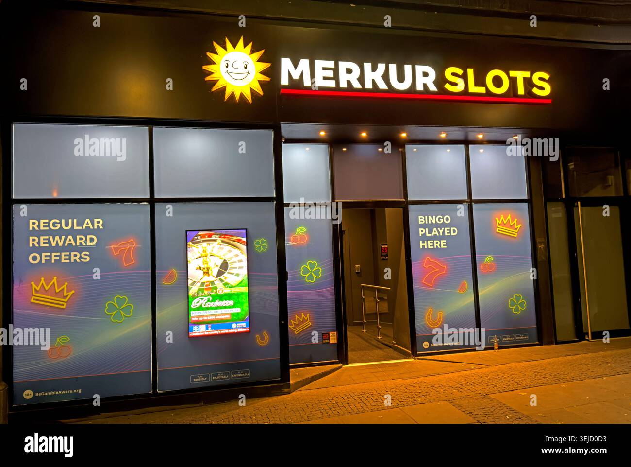 Illuminated Merkur Slots frontage in Warrington town centre, Cheshire, England, showing high street gambling and late-night gaming culture Stock Photo