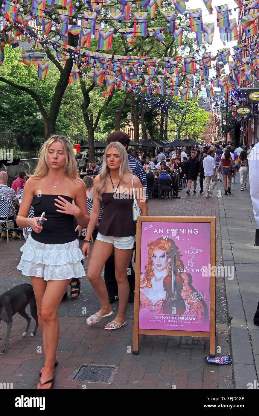 Crowds outside Bar Pop on Canal Street, Manchester, with summer drinkers, Pride flags and entertainment signage in the Gay Village. Stock Photo