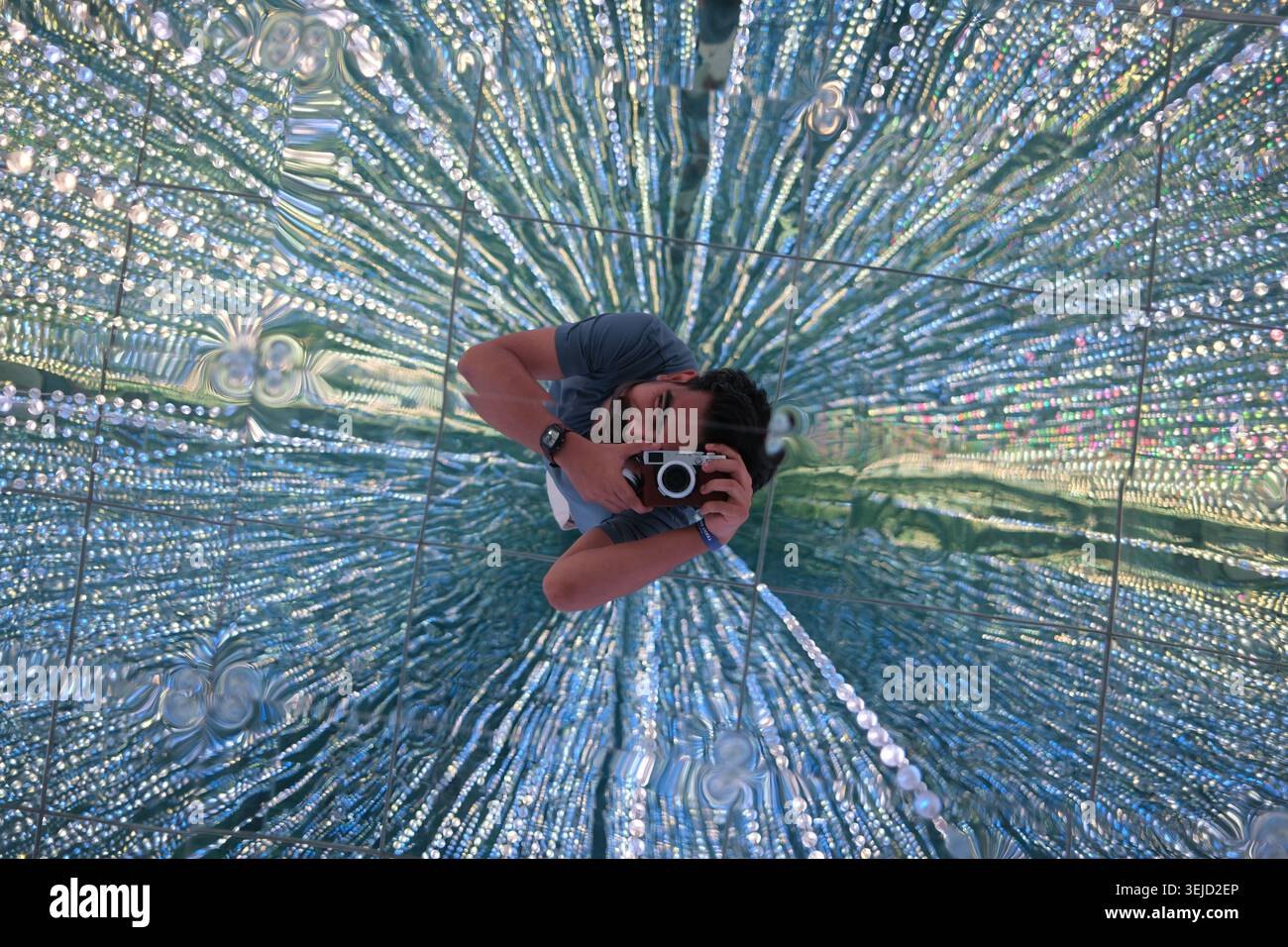 Photographer taking a self portrait reflection in a radial textured glass mirror creating a hypnotic and starburst light effect Stock Photo