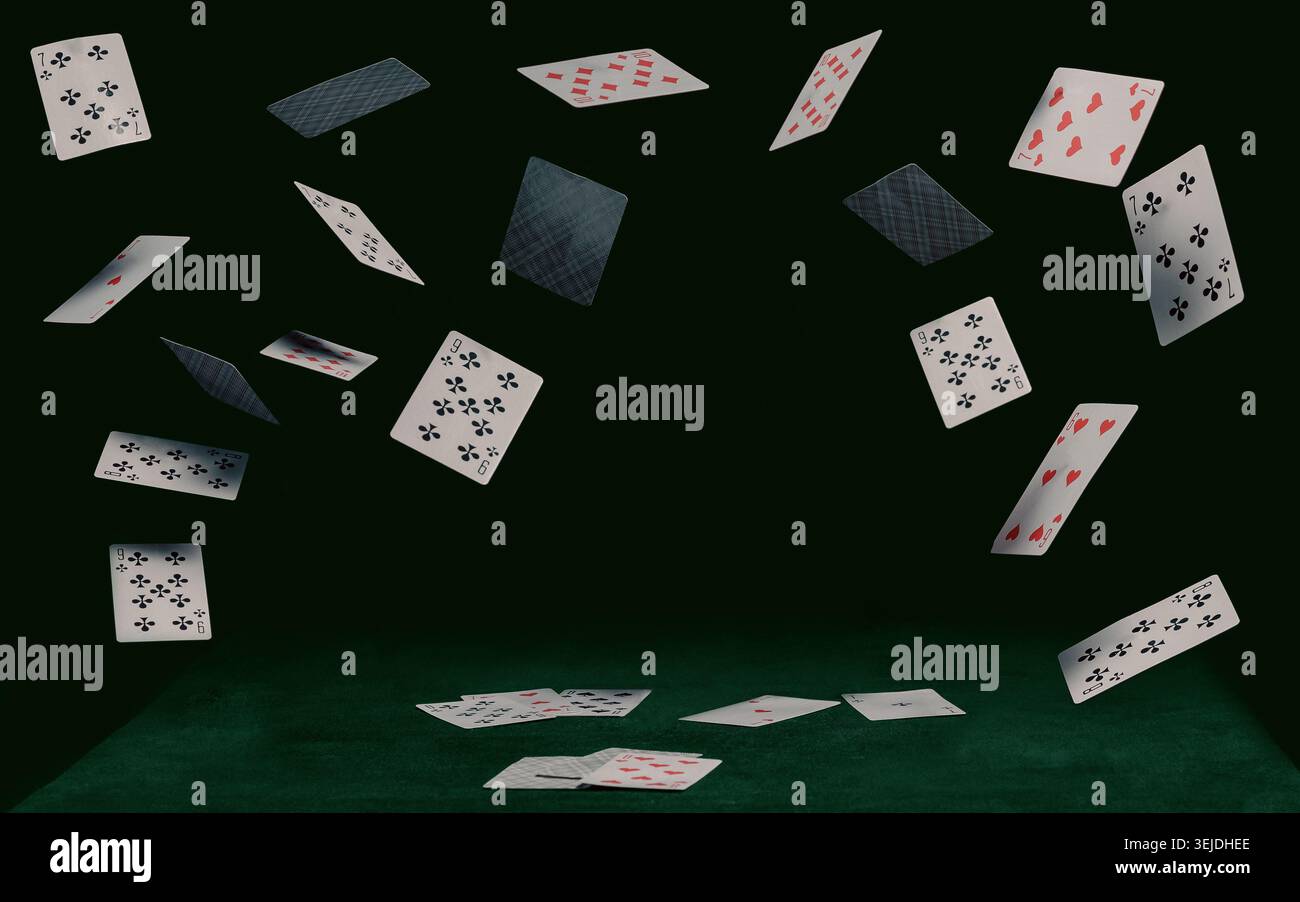 Playing cards fall on a green table Stock Photo