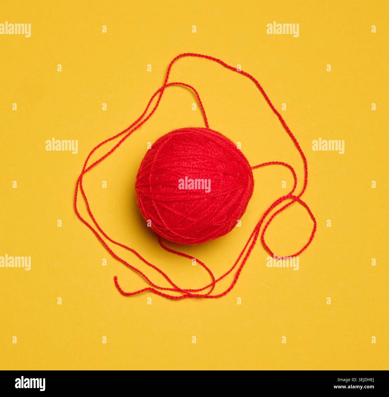 Ball of red woolen thread on yellow background, top view Stock Photo