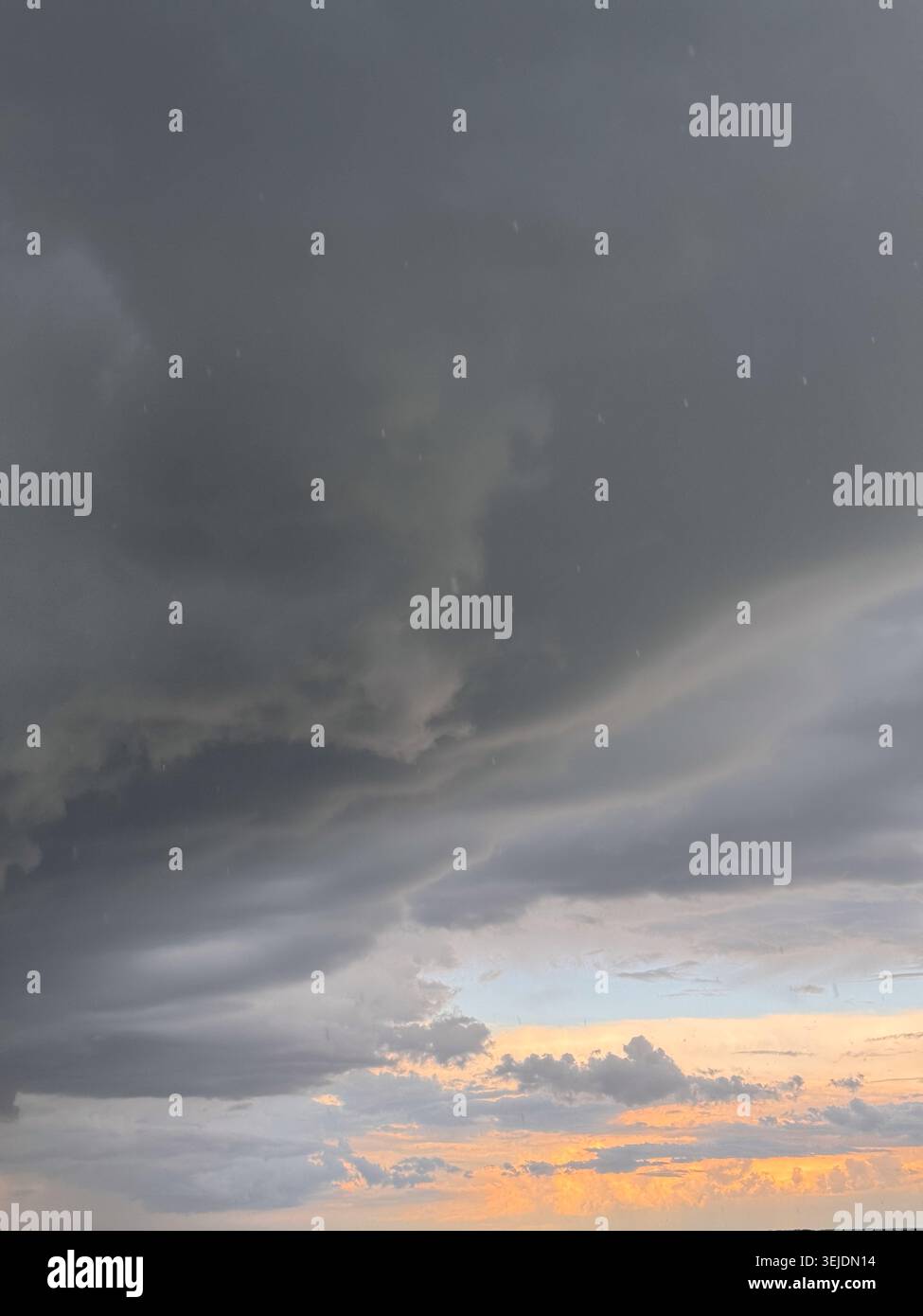Rain falls from moody clouds at dusk Stock Photo