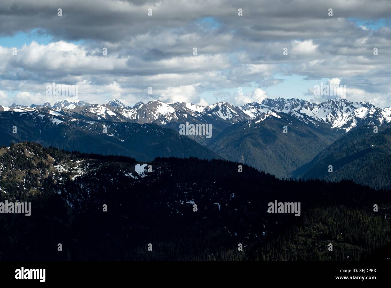 Snow capped mountains under a dramatic cloudy sky Stock Photo