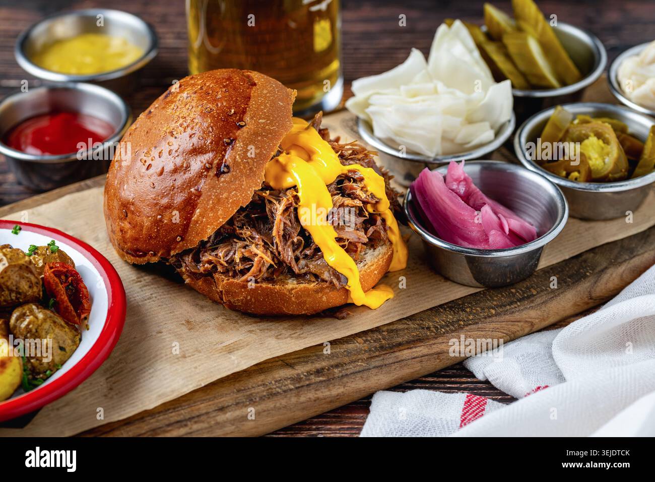 Slow cooked pulled rib beef burger with melted cheese and sides Stock Photo