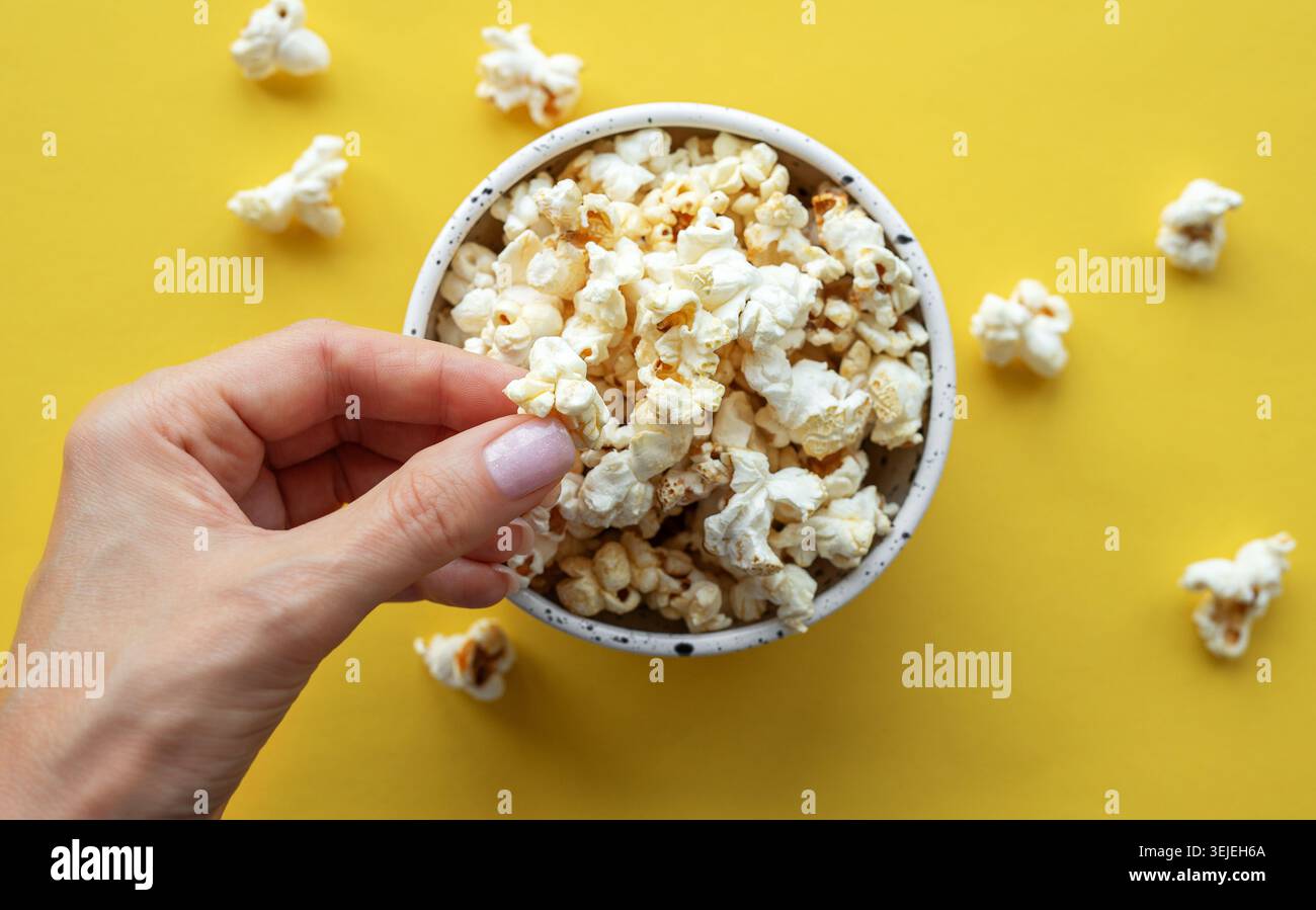 A woman's hand takes popcorn from a cup. Stock Photo