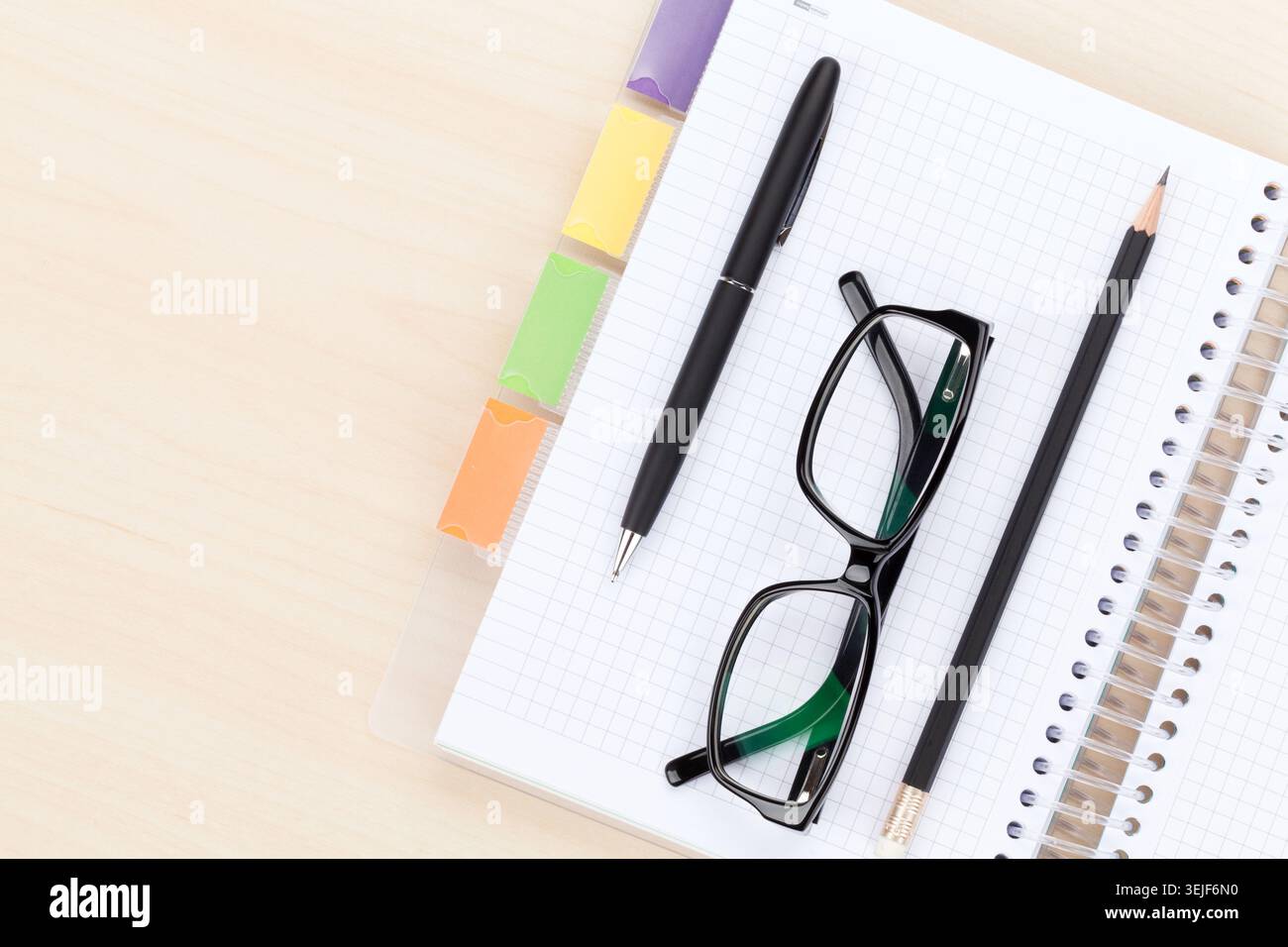 Office table with glasses over notepad, pen and pencil Stock Photo