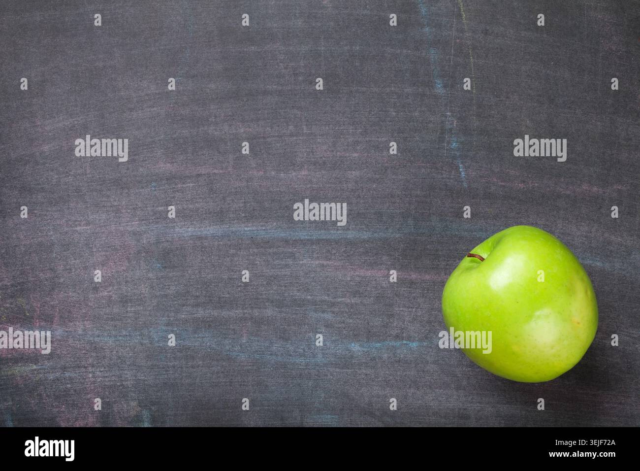 Green apple on blackboard or chalkboard background Stock Photo