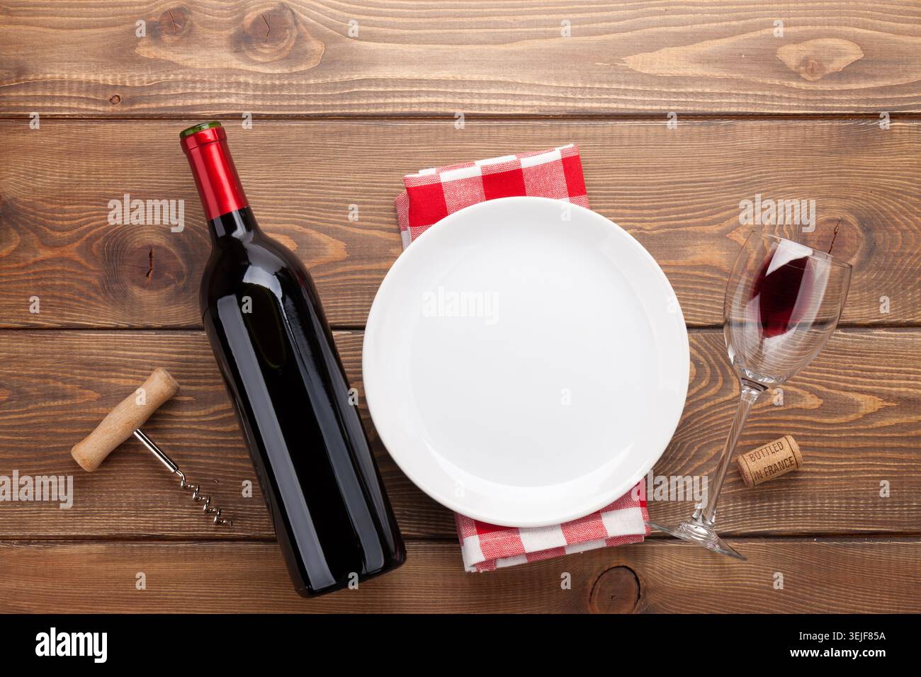 Table setting with empty plate, wine glass and red wine bottle Stock Photo