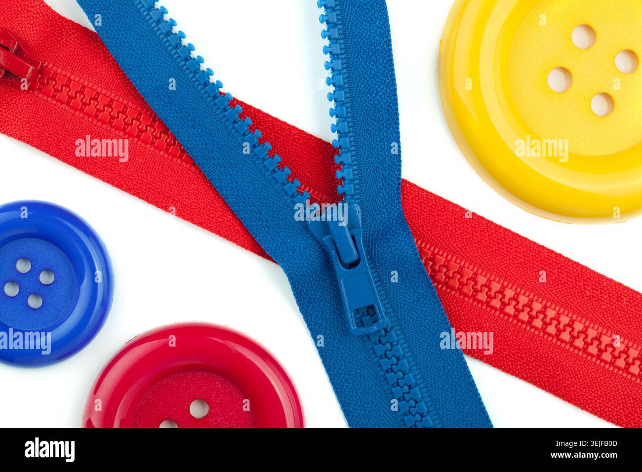 Three colored sewing buttons and two zippers closeup Stock Photo