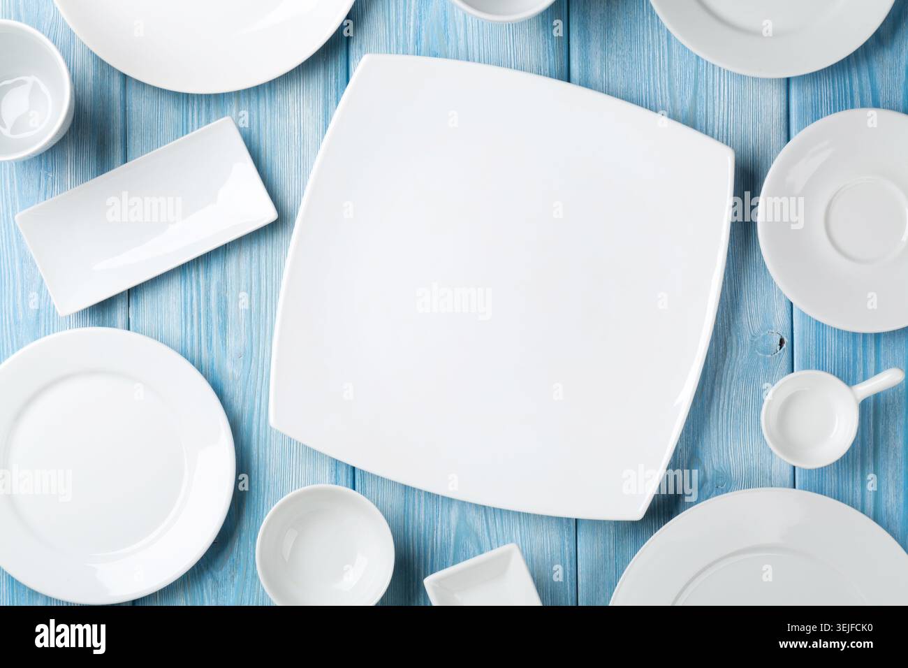 Empty plates and bowls on blue wooden background Stock Photo