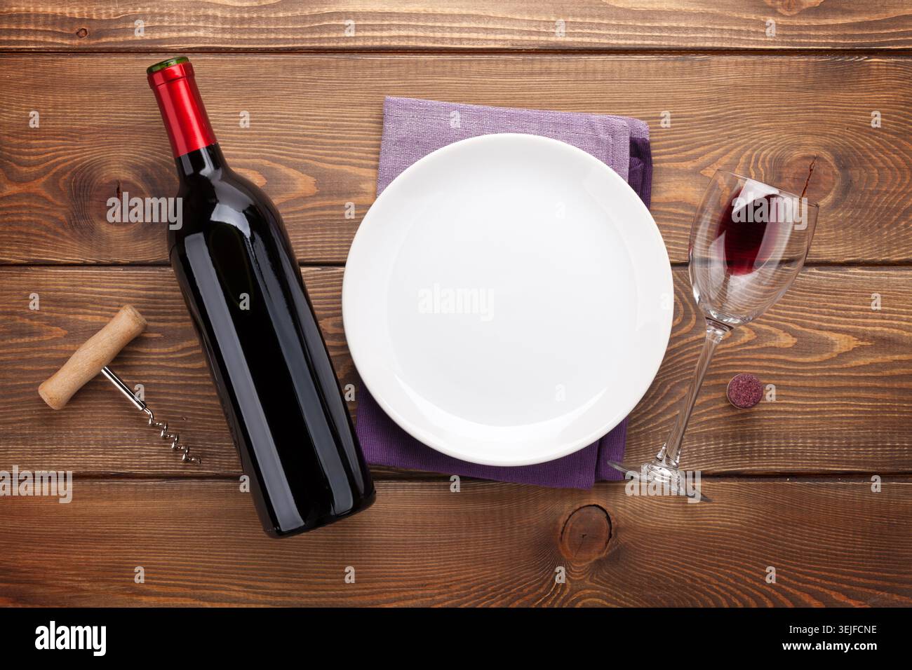 Table setting with empty plate, wine glass and red wine bottle Stock Photo