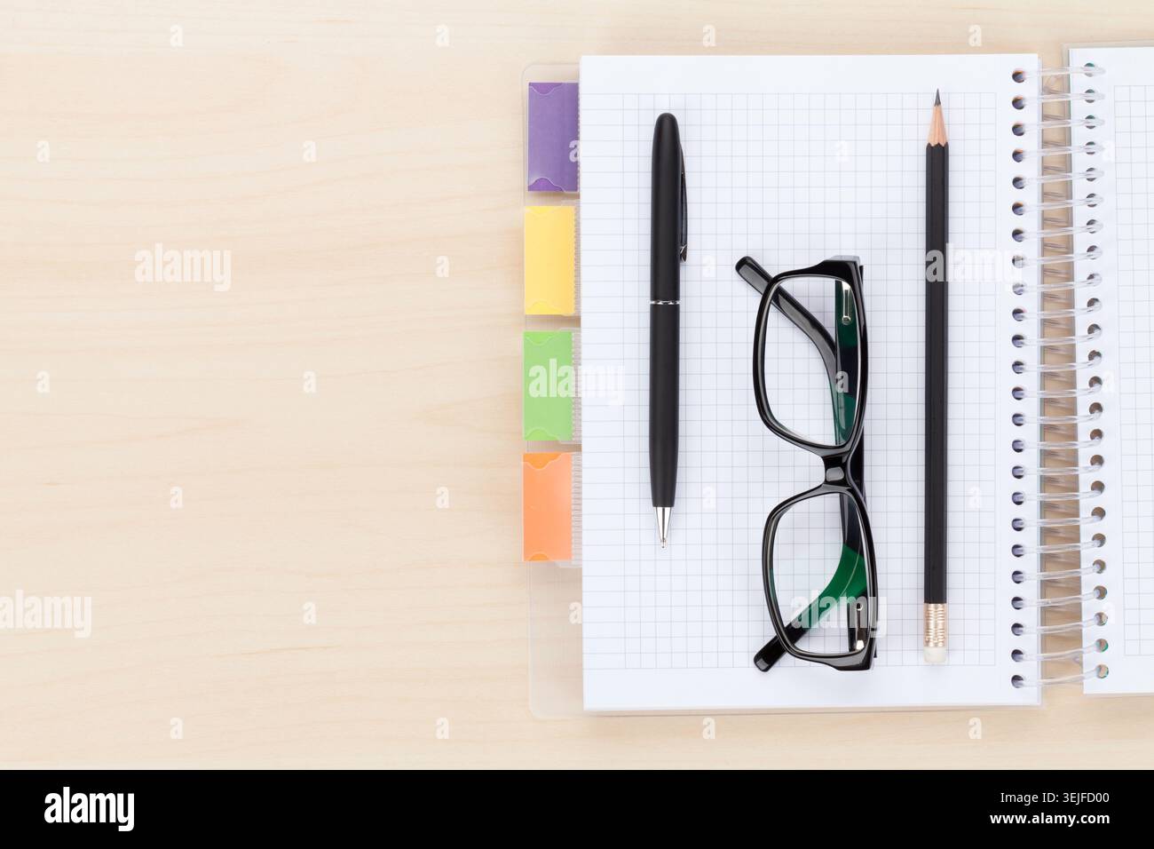Office table with glasses over notepad, pen and pencil Stock Photo