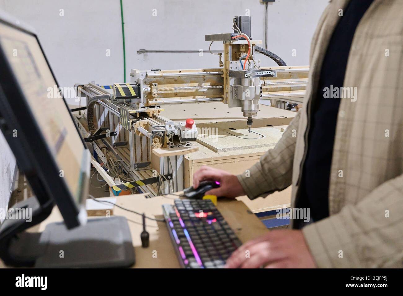 Operator Entering Coordinates on Computer for CNC Machine to Precisely Cut Wooden Pieces Stock Photo