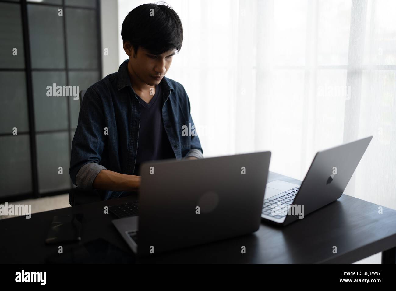 Asian man software engineer Working on Computer at office desk for writing program code IT Software Engineer finding errors tech support devops creati Stock Photo