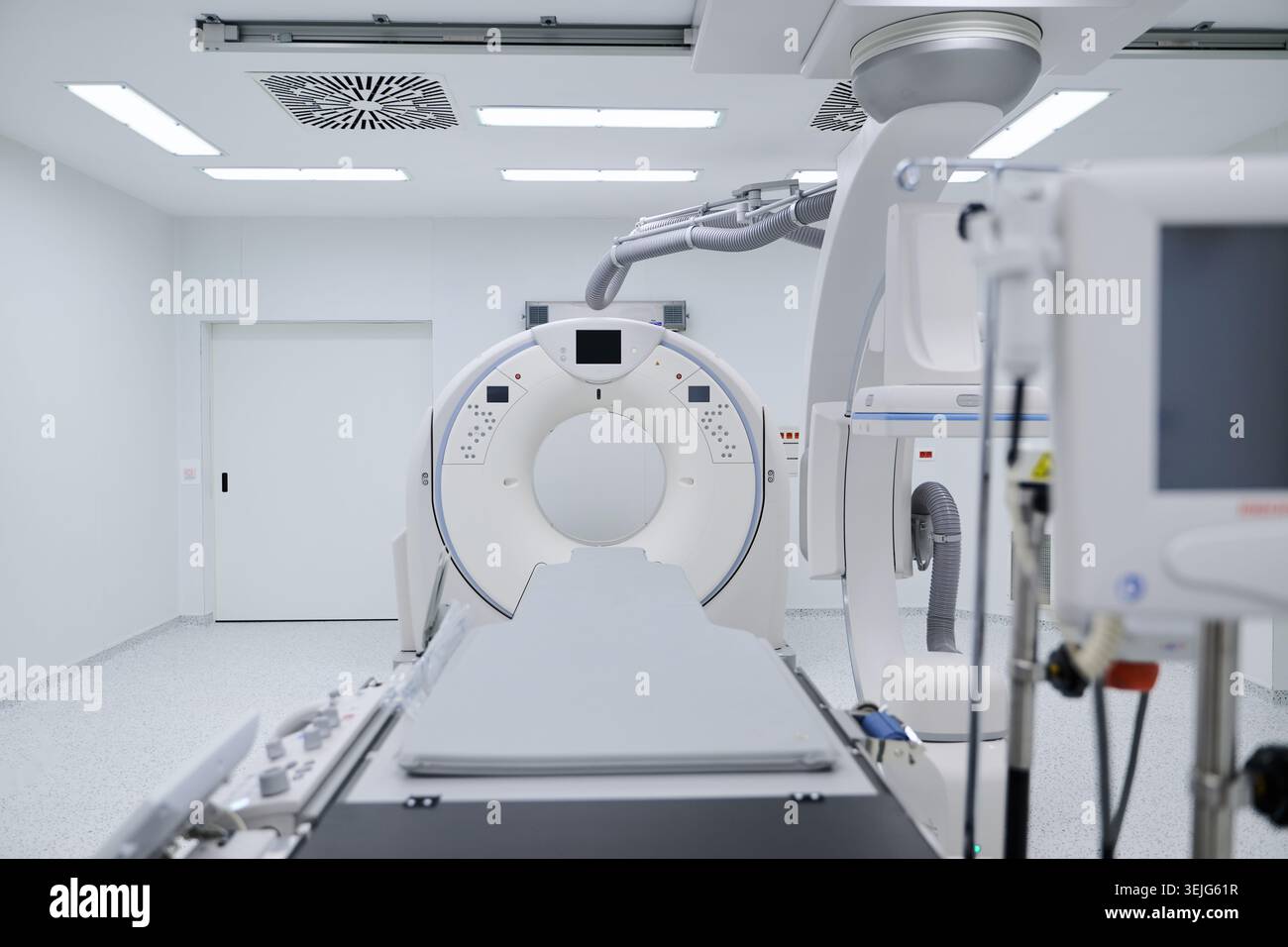 A modern CT scanner is positioned in a bright examination room ...