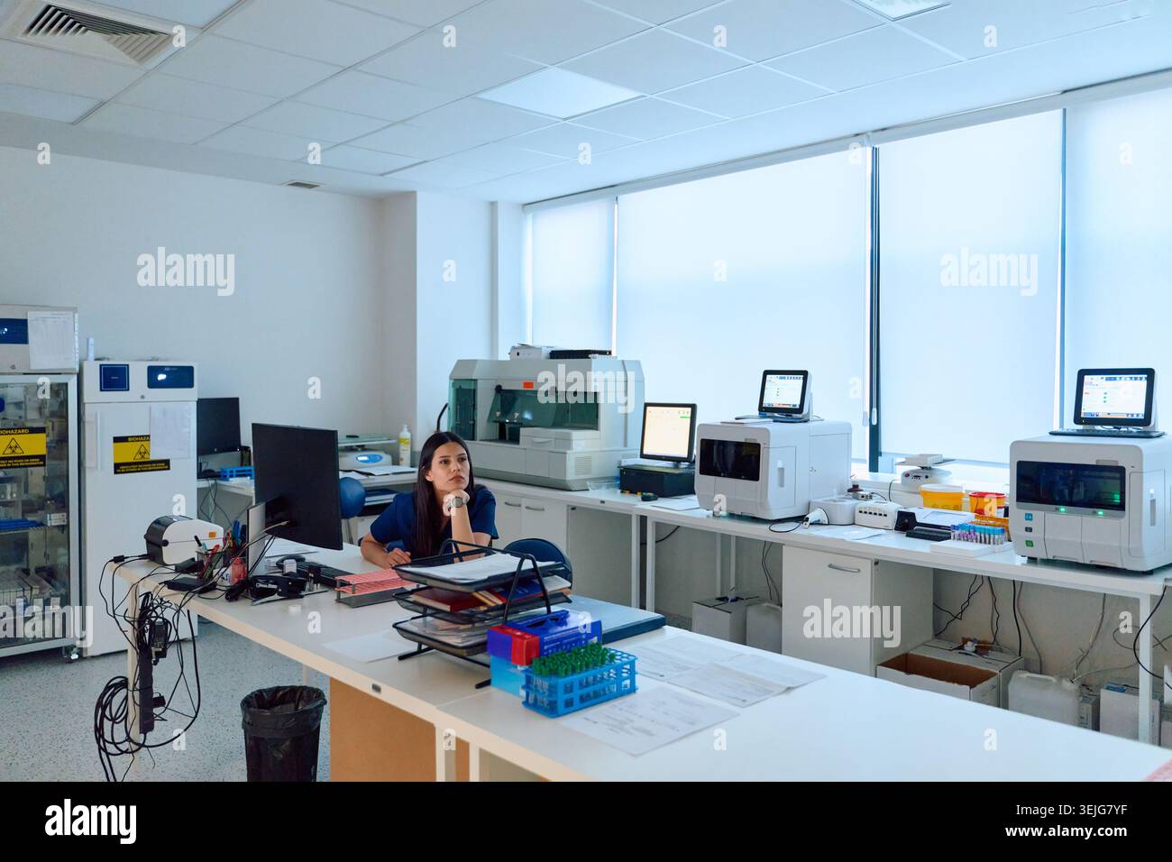 Laboratory setting featuring a female scientist engaged in research work amid advanced equipment and a clean workspace during da Stock Photo