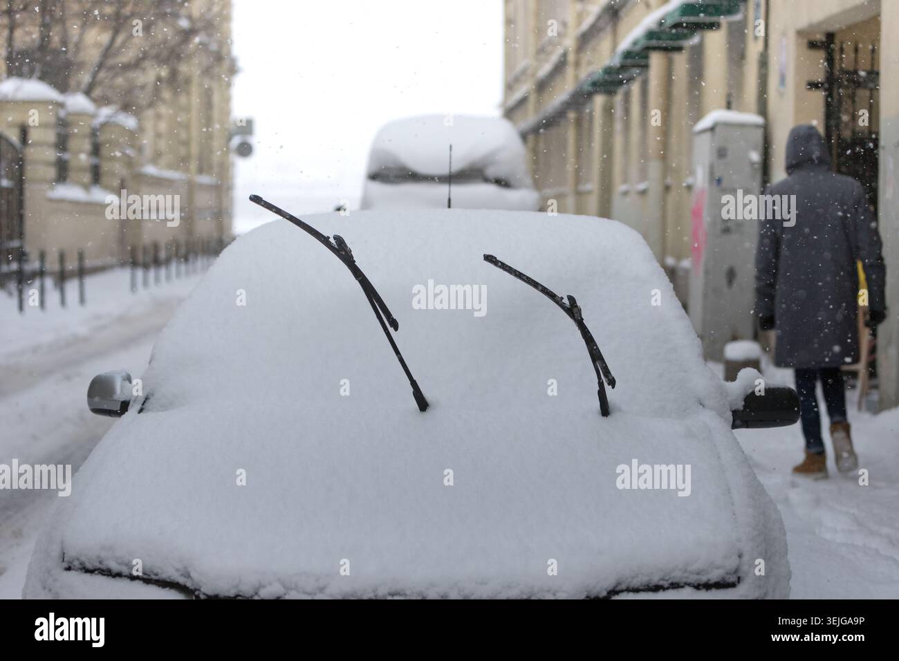 Car is fully covered with snow after snowstorm, windshield wiper raised up. Winter time in Europe Stock Photo
