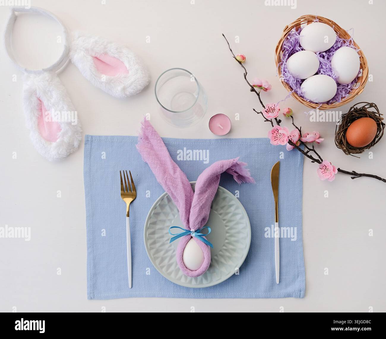 Easter table setting, egg with bunny ears on plate on the table decorated for Easter, top view Stock Photo