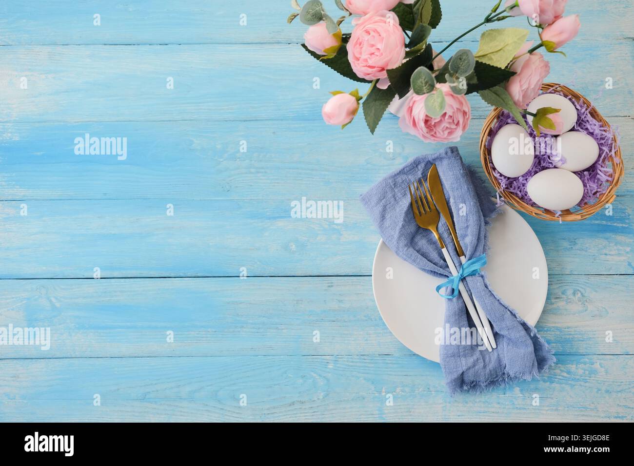Easter table setting, eggs with cutlery on plate on table decorated for Easter, top view flat lay Stock Photo