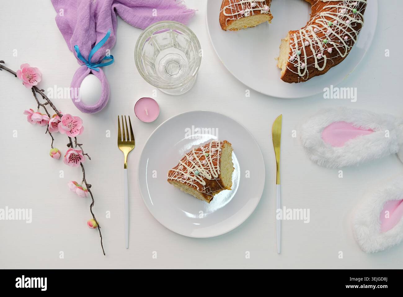 Top view Easter table setting, glazed Easter cake and candles on table decorated for Easter Stock Photo