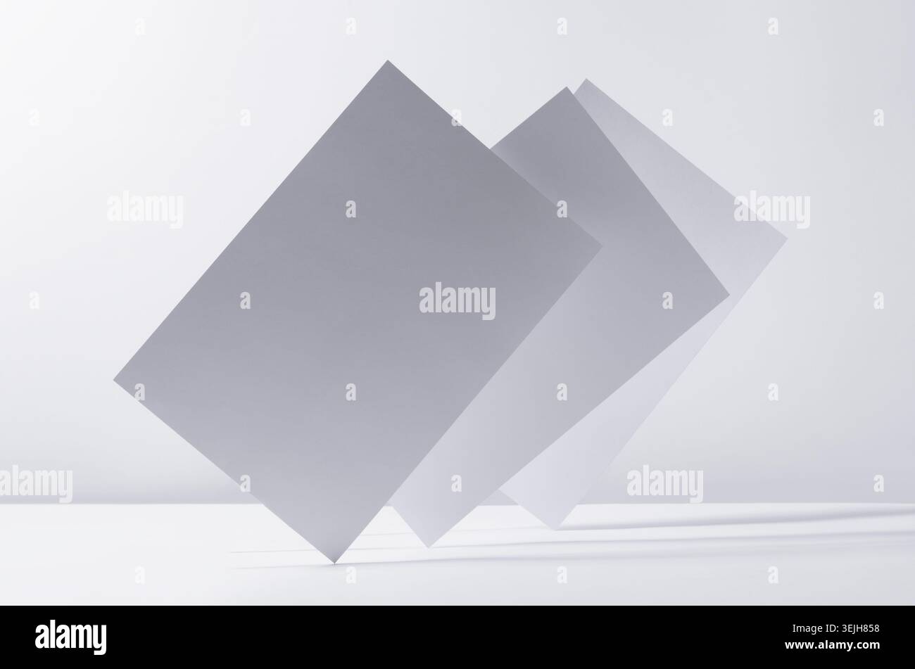 Abstract white grey minimalist background with flying papers in light with shadow as blank copy space. Stock Photo