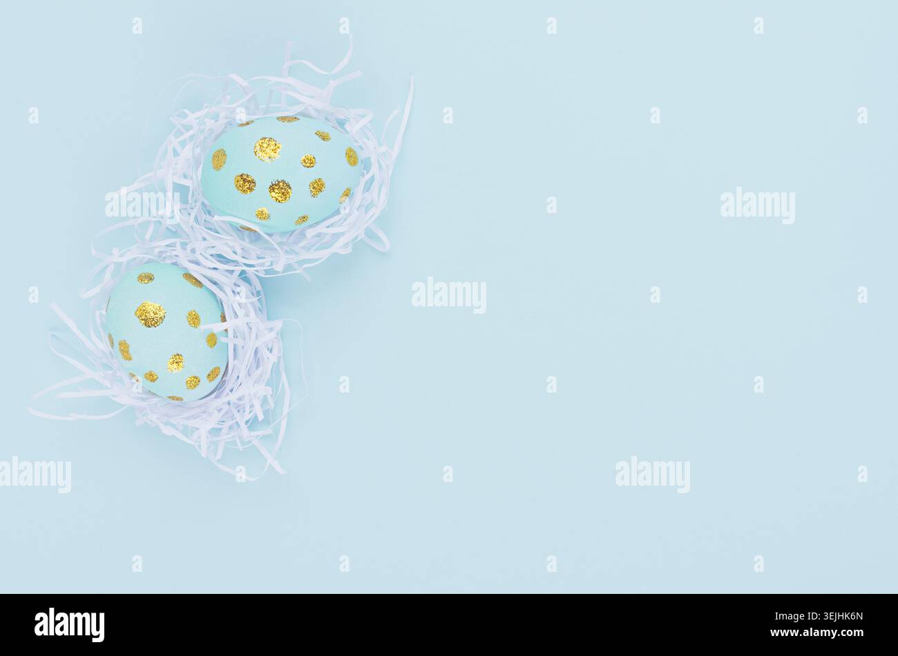 Easter background - easter eggs with golden dots in white nest on blue backdrop, top view. Stock Photo