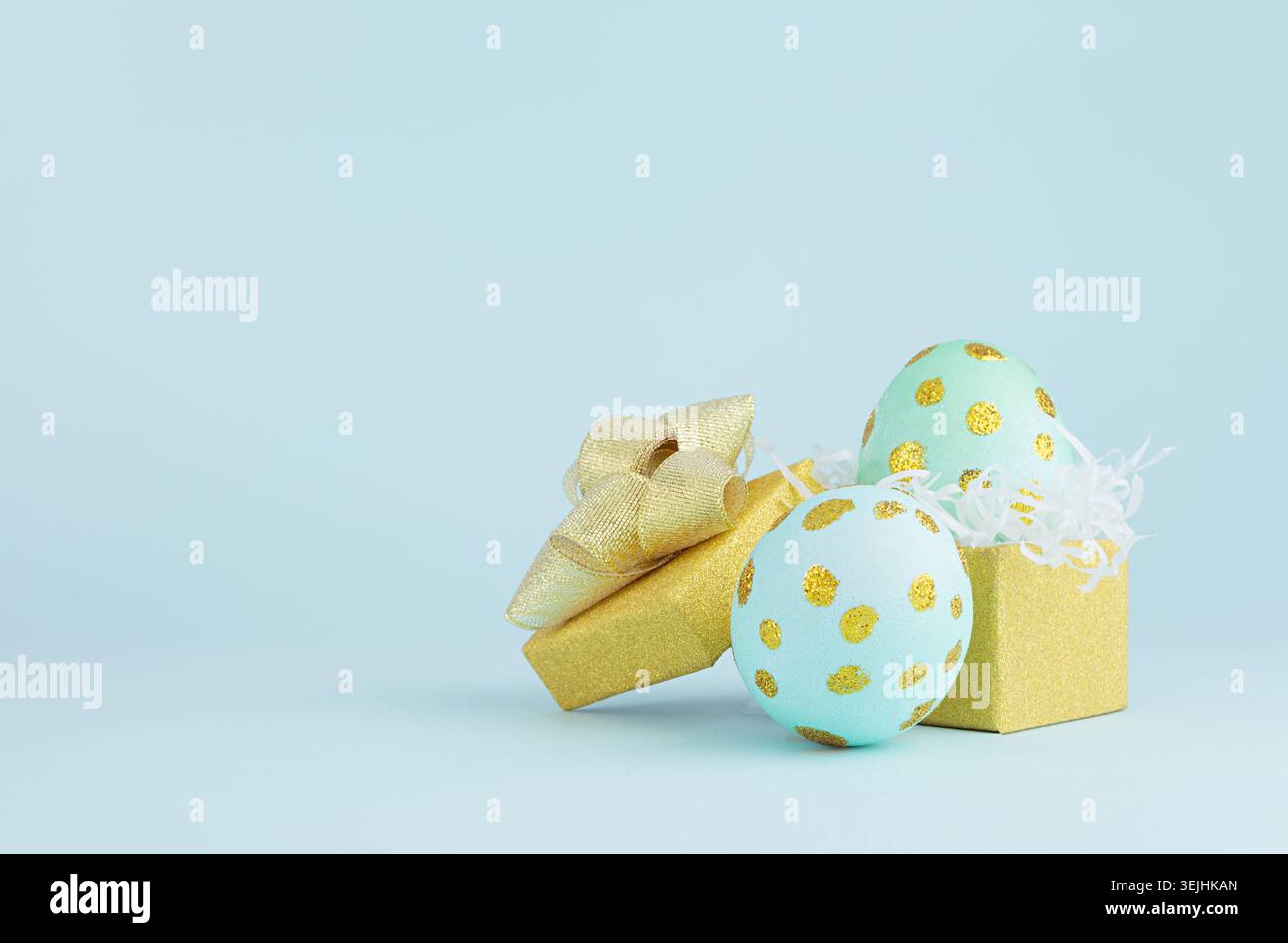 Stylish easter background with blue easter eggs with gold dots and gift box on blue background. Stock Photo