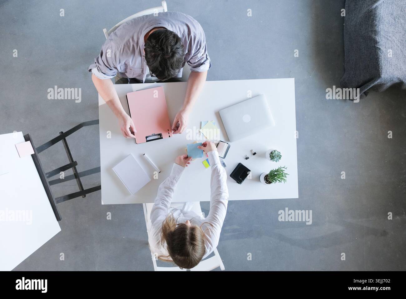 Millennial man and woman working in small office discussing documents, top view Stock Photo