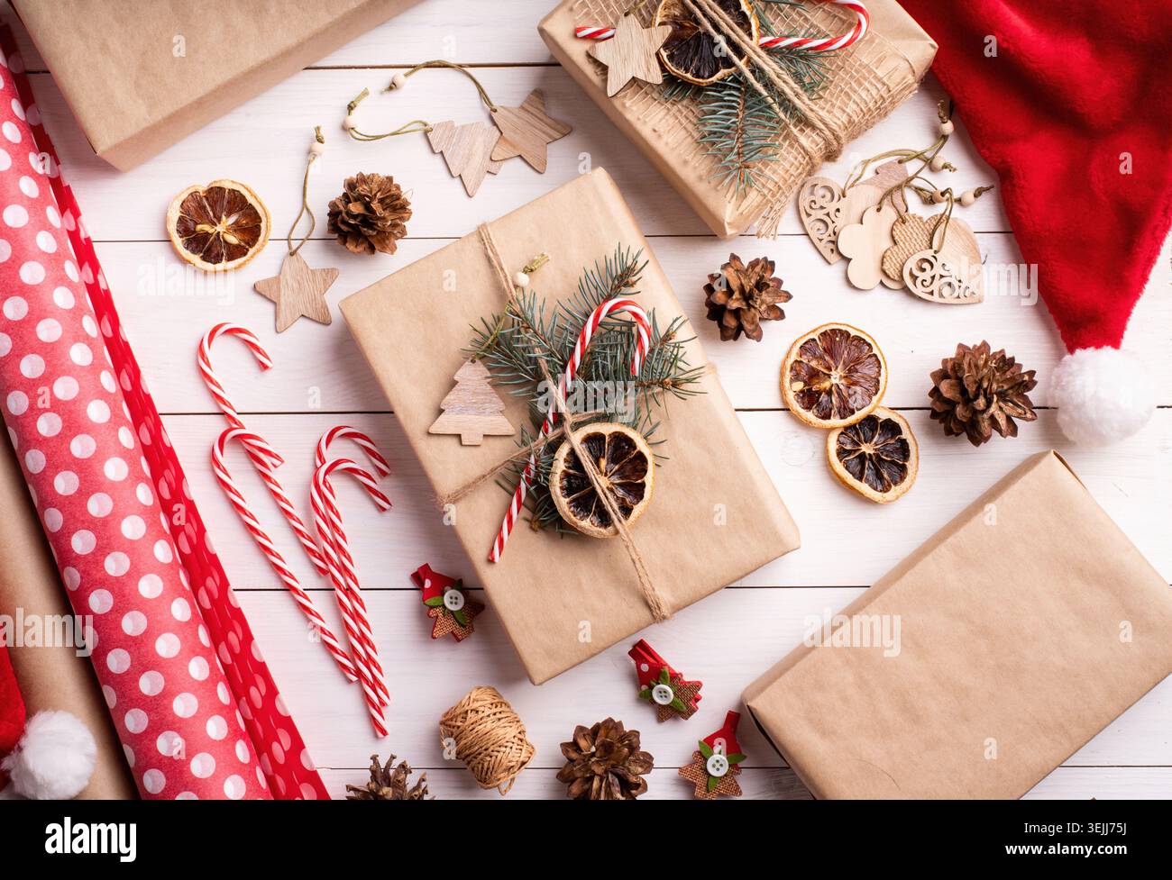 Gift boxes wrappaed in craft paper decorated with pine cones, candy canes and fir tree branches top view flat lay Stock Photo