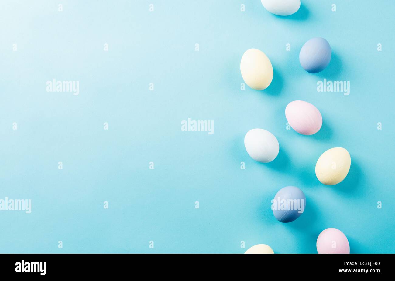 Pastel colored easter eggs on blue background with copy space Stock Photo