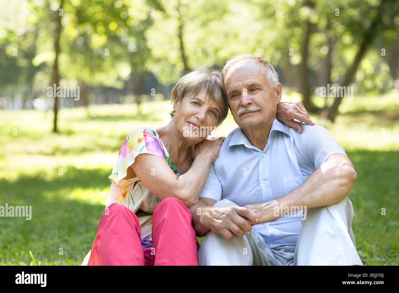 Happy Elderly Senior couple sitting on grass together relaxing in the garden. Stock Photo