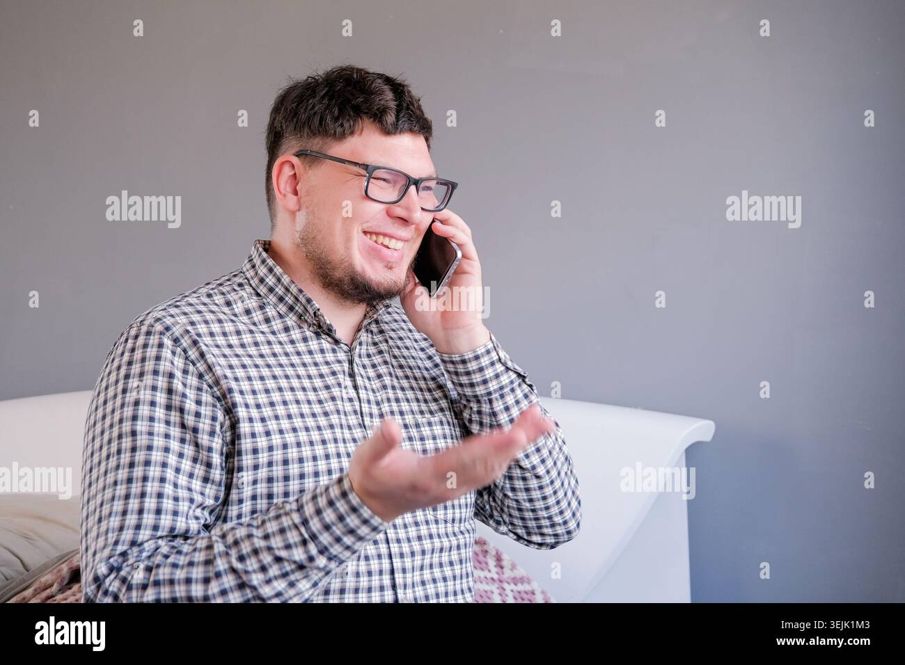 Man sitting on the bed using smartphone having a call Stock Photo