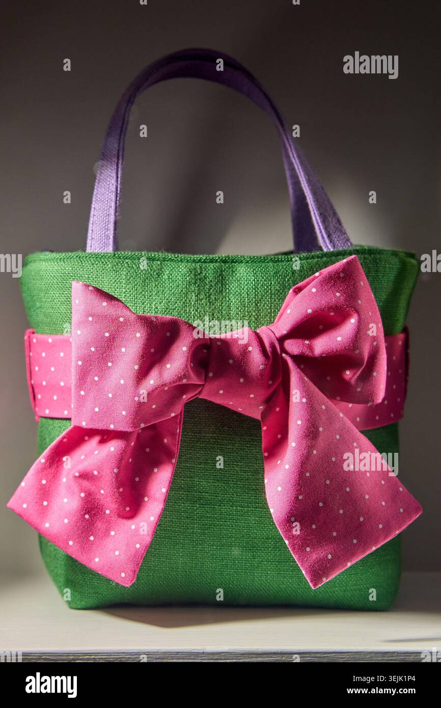 Green handmade fabric gift bag decorated with a large pink polka dot bow. Stock Photo
