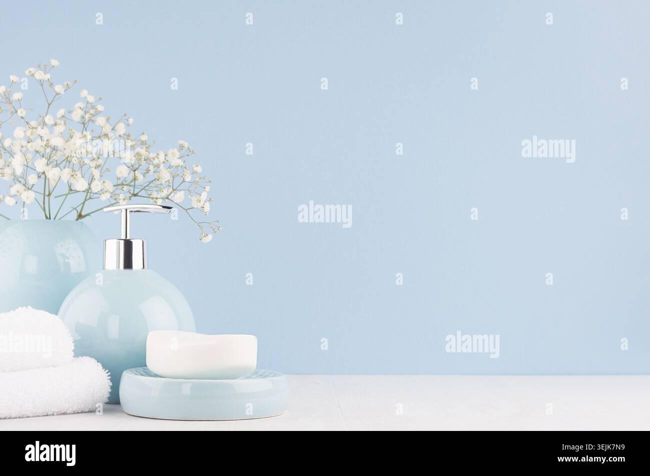 Bathroom interior - ceramic accessories - light blue circle vase with white flowers, soap dispenser , fluffy towels on white woo Stock Photo