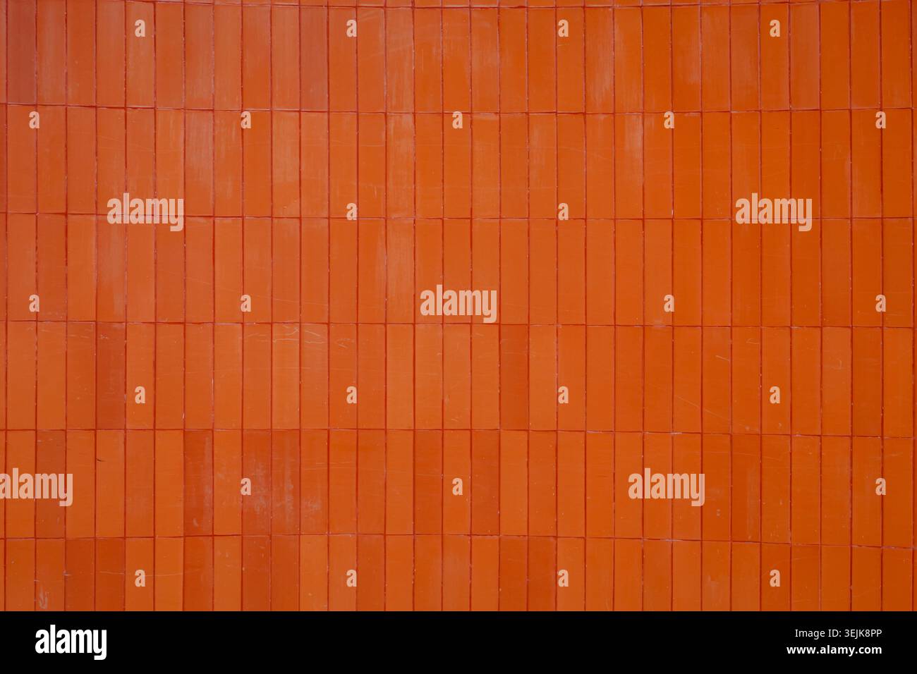 Modern architectural background featuring vertical orange ceramic wall cladding. Stock Photo