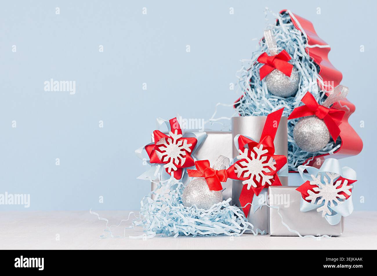 Colorful christmas home decoration -  metallic gift boxes with bright red and blue silk ribbons and christmas tree on white wood Stock Photo