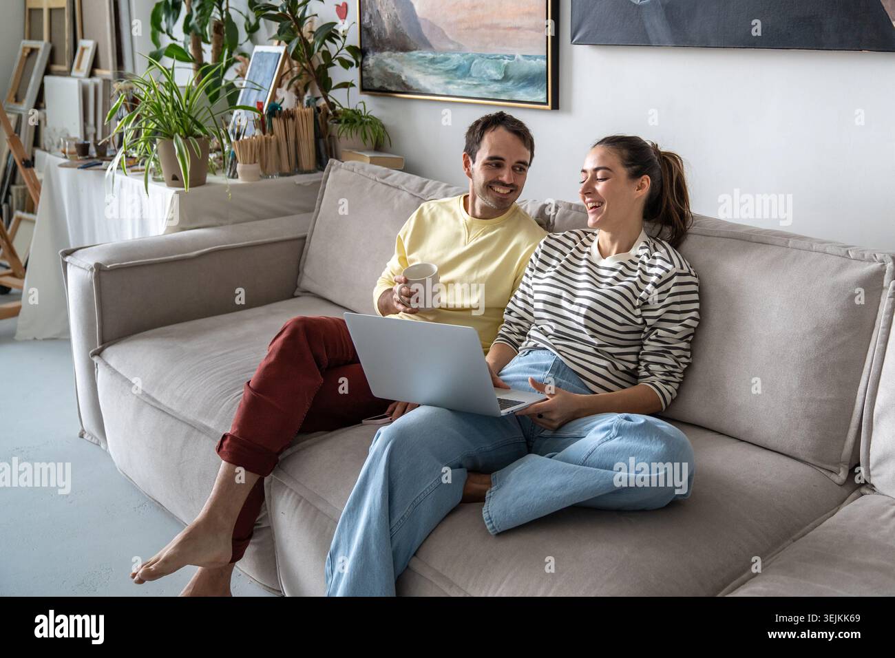 Happy family married couple man and woman enjoying watching comedy movie on laptop together. Stock Photo