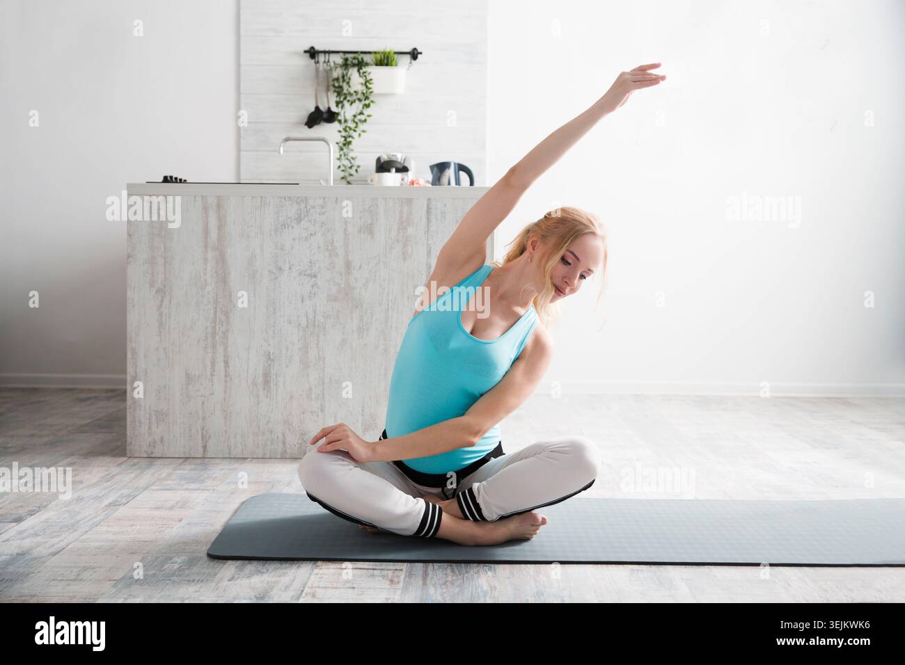 Young pregnant woman doing stretching and yoga in the morning at home. Stock Photo