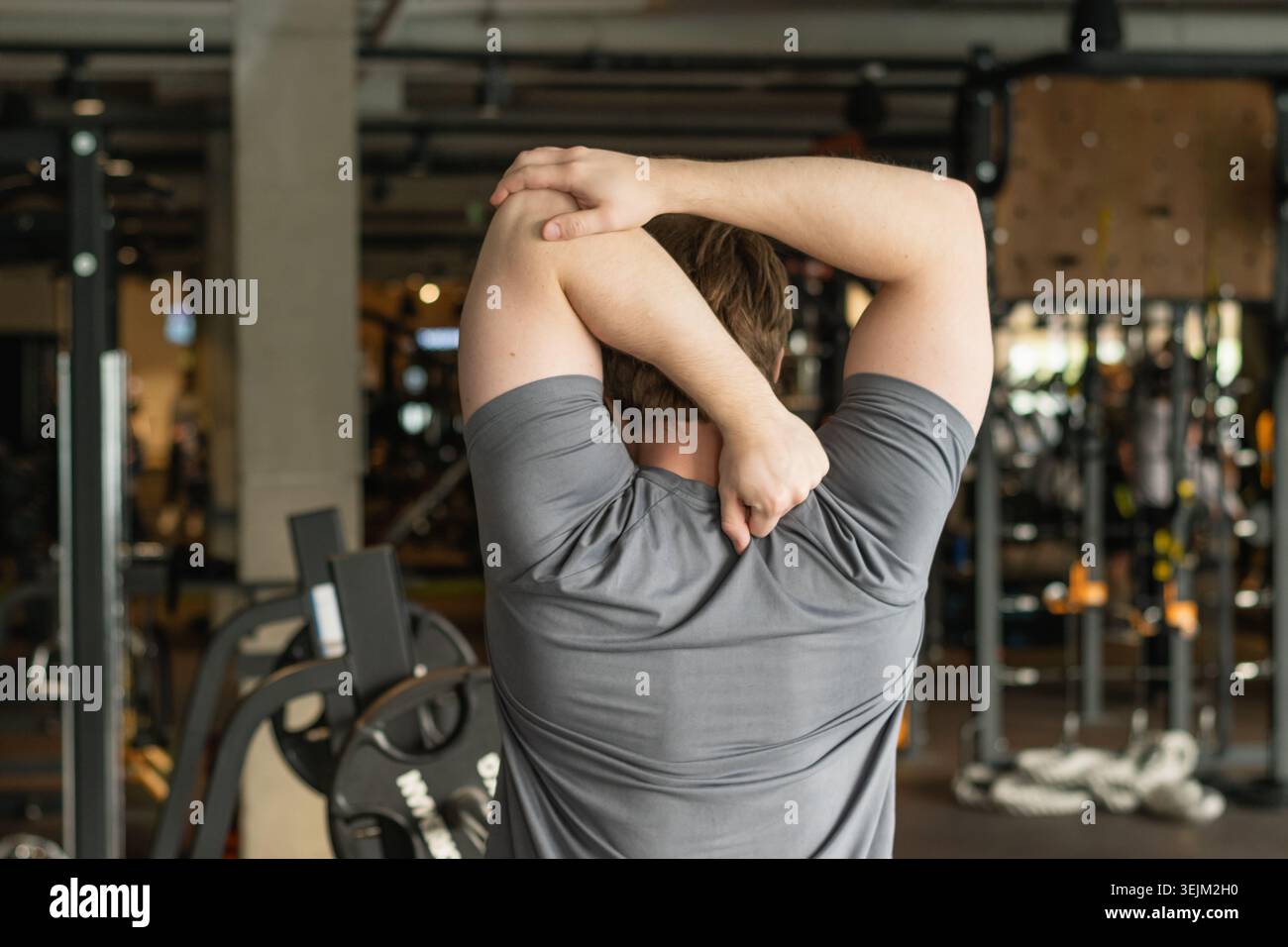 Athlete or caucasian young sporty man doing stretching back and arms. Back View Stock Photo